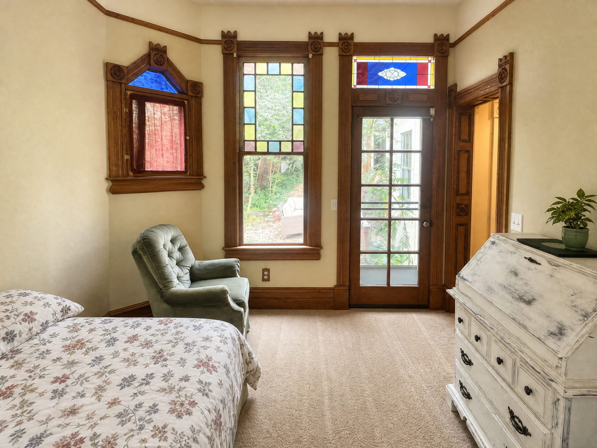 Bedroom with stained glass windows, balcony door, and antique dresser
